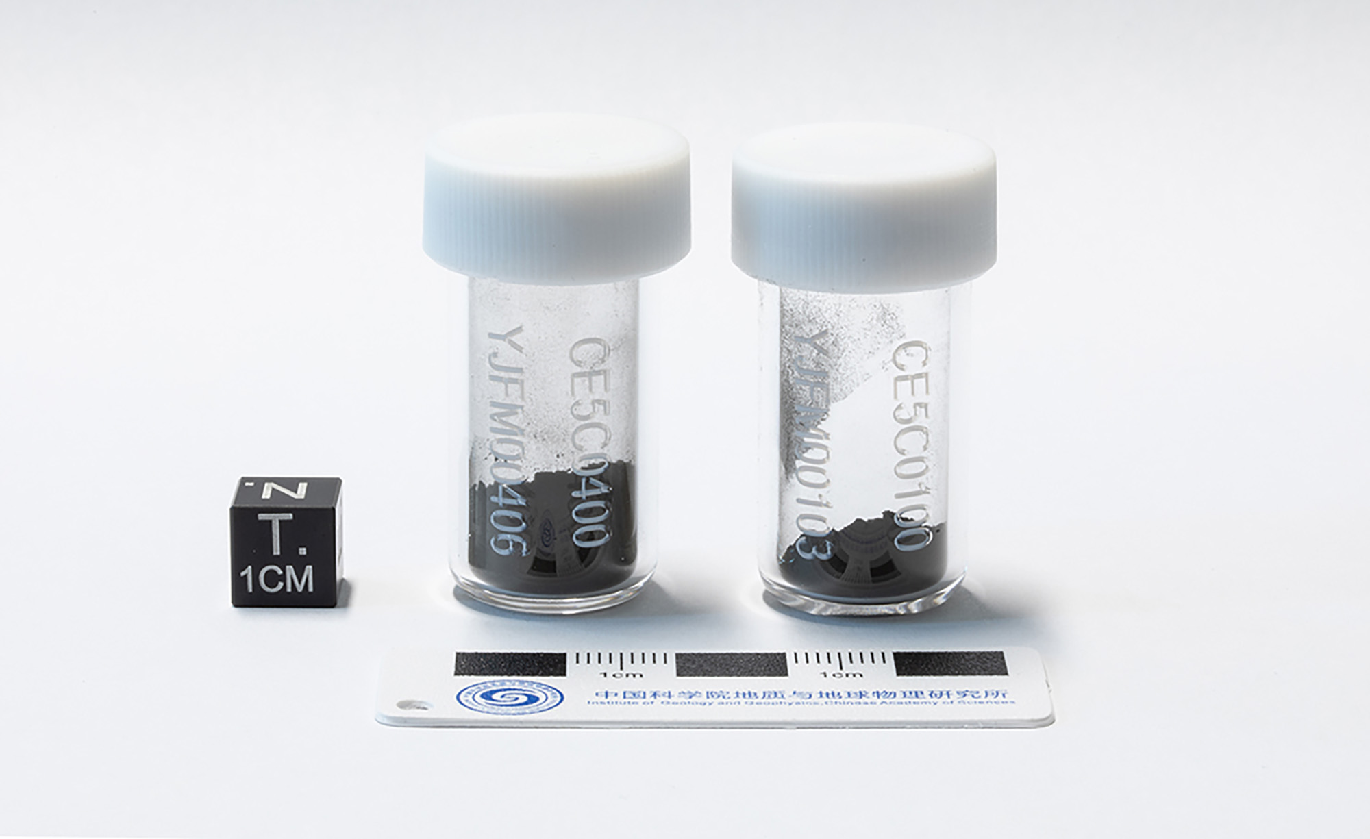 two labelled vials of soil next to a small ruler for scale